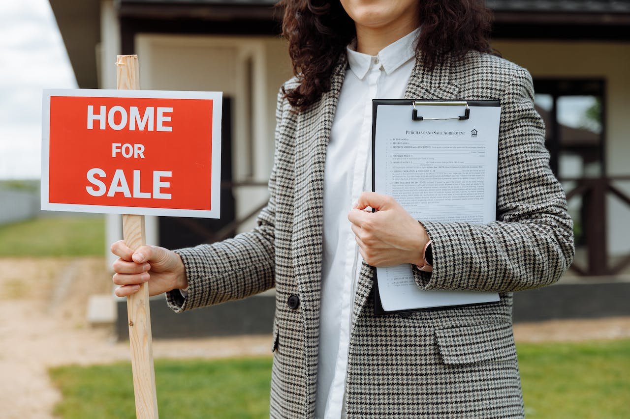 woman holding a home for sale sign